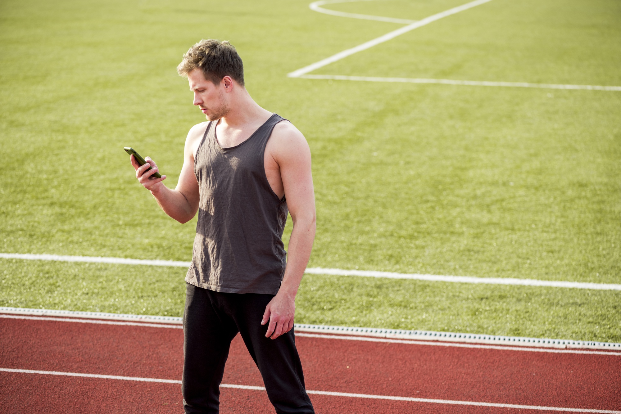 Sportif consultant son smartphone sur un terrain de sport