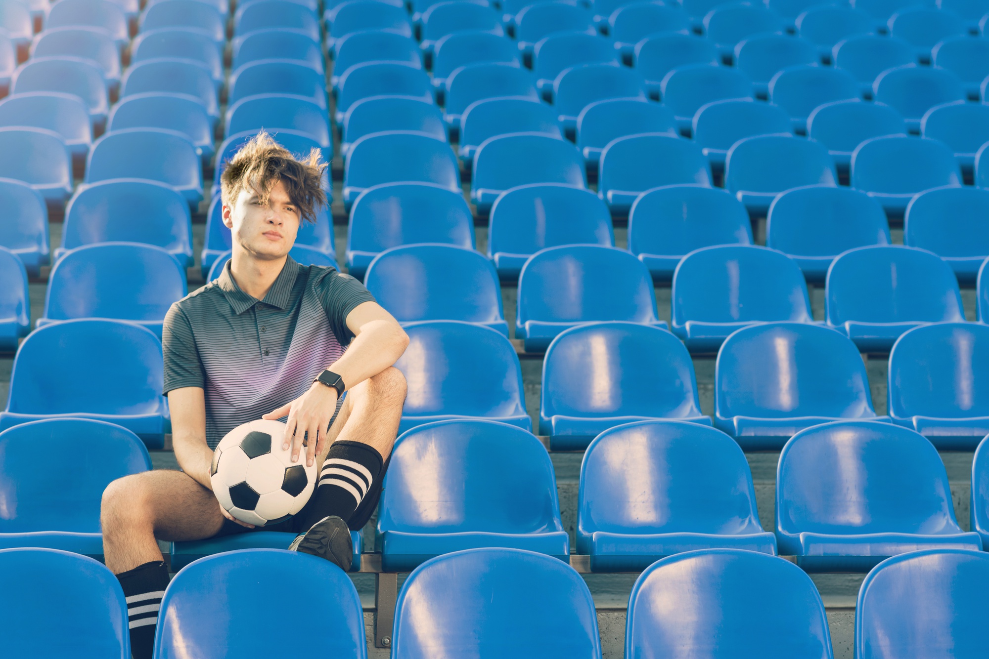 Joueur de football avec un ballon assis dans les tribunes d'un stade