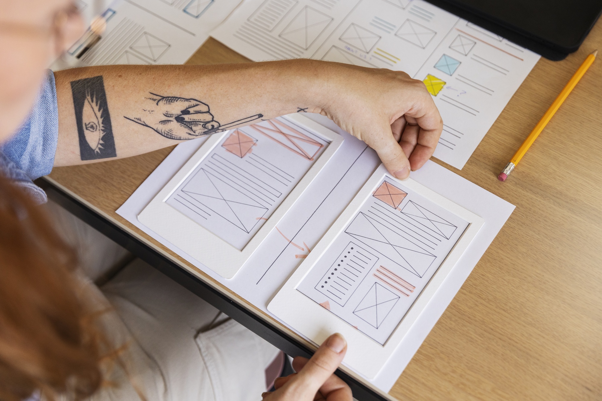 Maquettes d'interface posées sur un bureau lors d'un atelier de conception