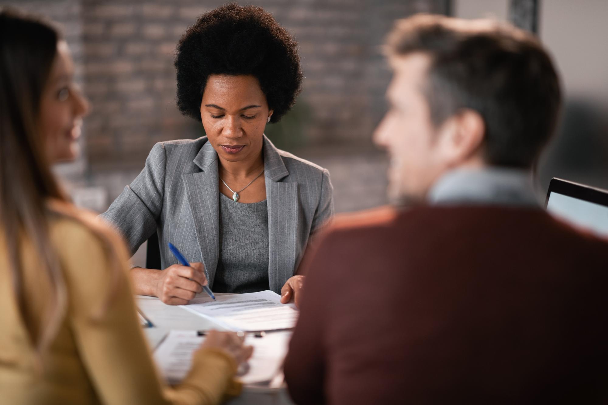 Conseillère en assurance recevant un couple lors d'un rendez-vous