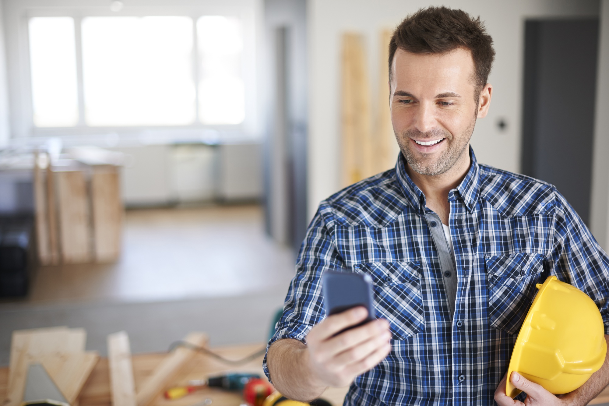 Artisan consultant son smartphone devant un chantier