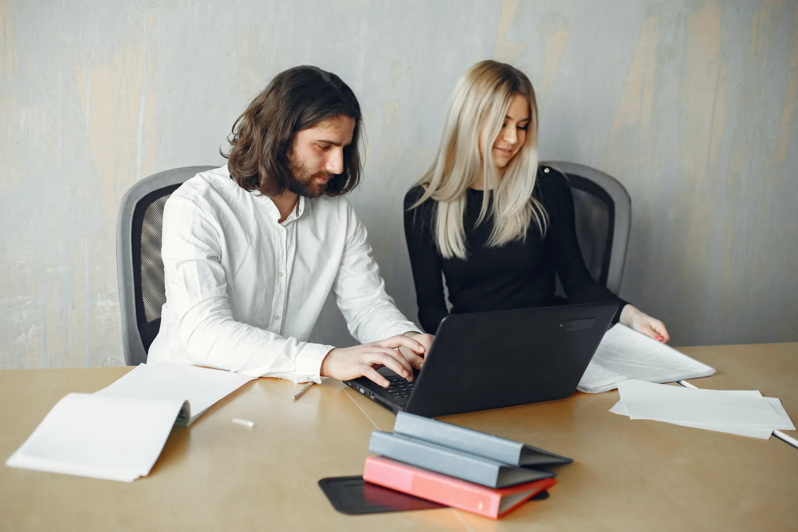 Deux collègues comparent des chiffres sur papier et sur un ordinateur portable